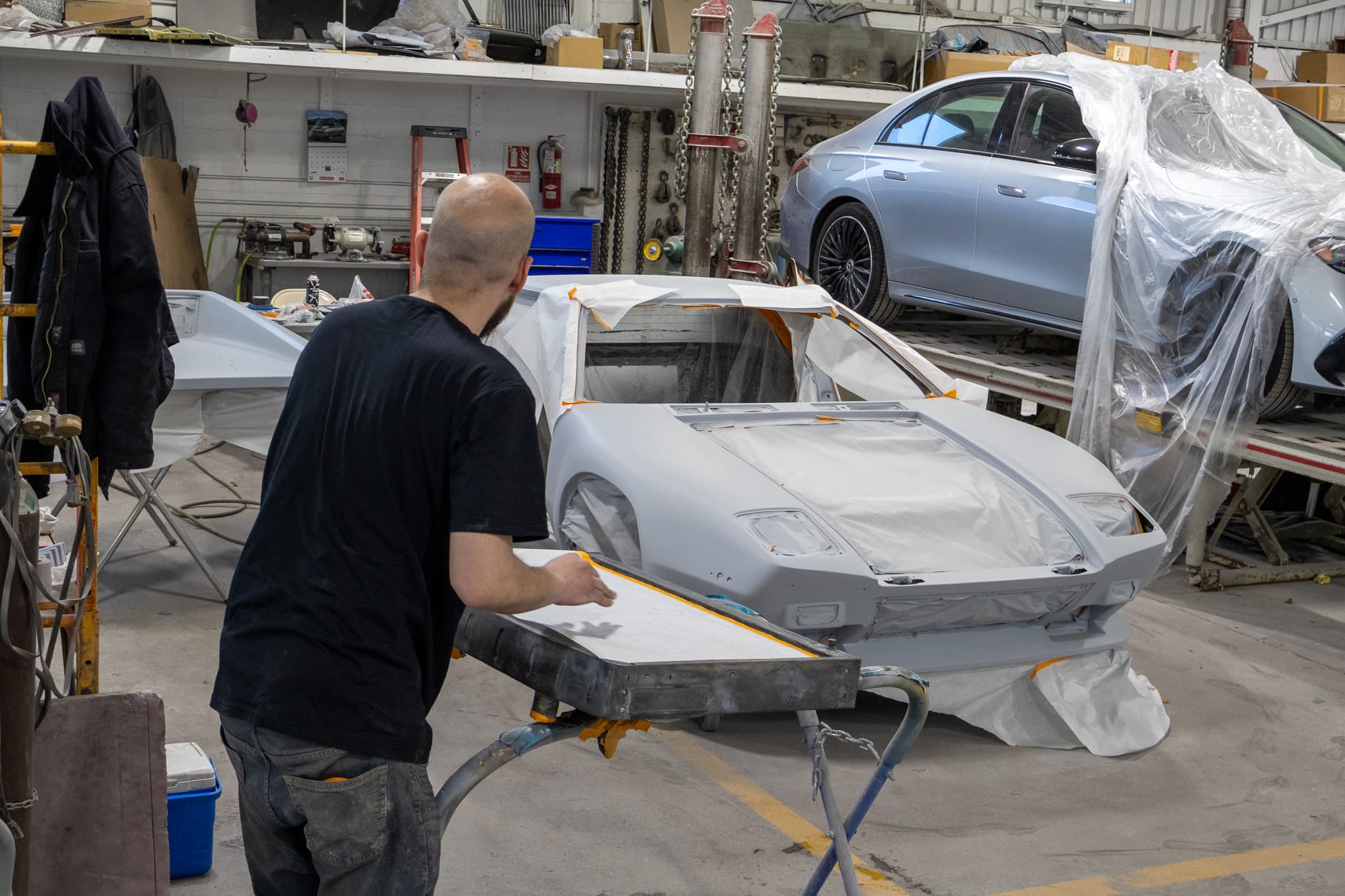 Technician finishing a primered panel before paint at Autometric Body & Paint