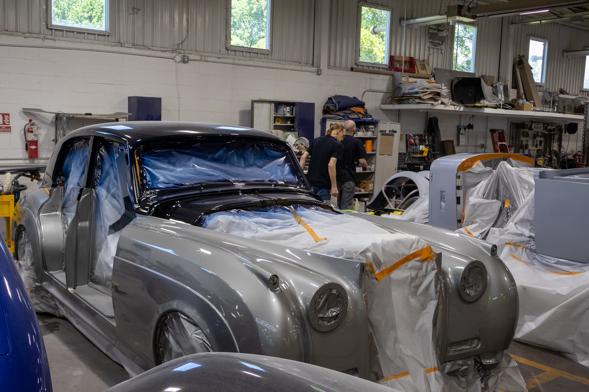 Silver classic luxury sedan masked off for restoration work at Autometric Body & Paint