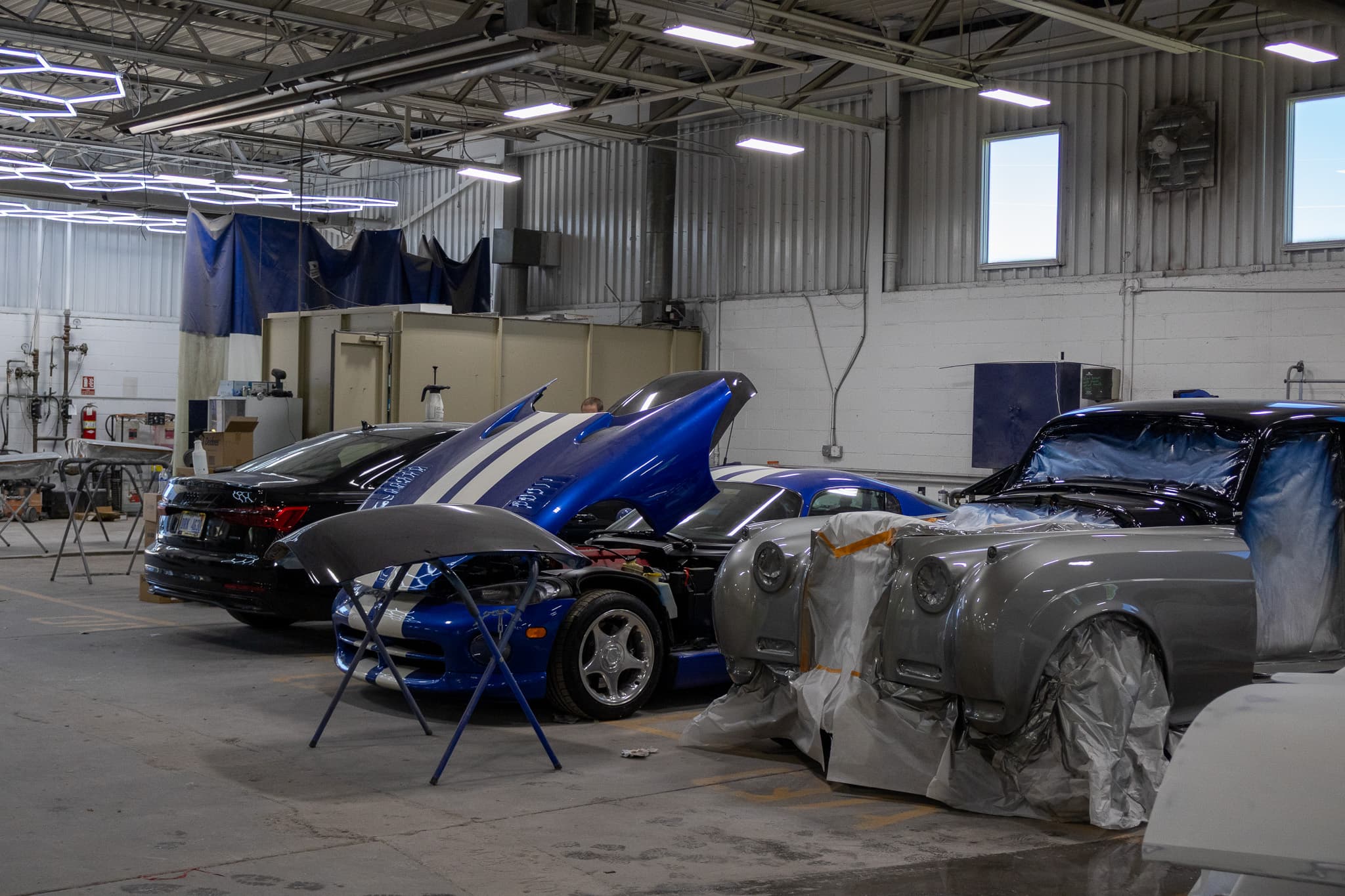 Collision, custom paint, and restoration projects lined up inside the Autometric Body & Paint shop in Pontiac, MI